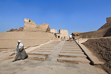 Man in jellabiya walking out of  the Temple of Horus, Edfu, Egypt, North Africa, Africa