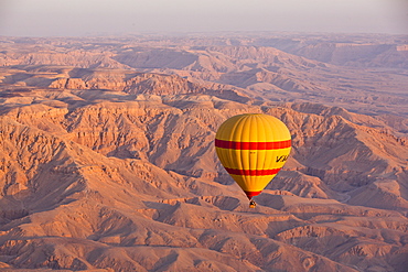 Hot air balloon suspended over the Theban hills of Luxor at sunrise, Thebes, Egypt, North Africa, Africa