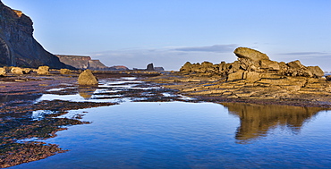 Rock formations at Saltwick Bay, with Black Nab and Saltwick Nab in the distance, North Yorkshire, Yorkshire, England, United Kingdom, Europe