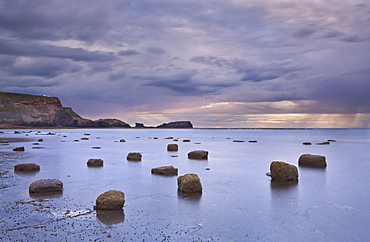 Giant boulders at low tide in Saltwick Bay with showery weather over Saltwick Nab, North Yorkshire, Yorkshire, England, United Kingdom, Europe