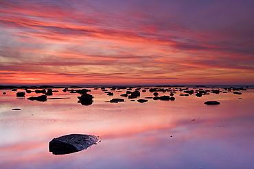 Boulders and reflections in the sea at sunrise, Saltwick Bay, Yorkshire, England, United Kingdom, Europe