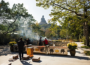 People lighting incense at Po Lin Monastery with Big Buddha statue in background, Lantau Island, Hong Kong, China, Asia