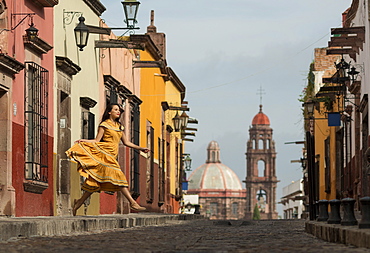 Young woman dancing down cobbled street (recreo), San Miguel de Allende, Guanajuato, Mexico, North America