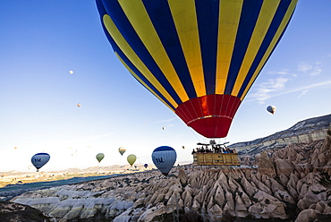 Hot air balloons flying among rock formations at sunrise in the Red Valley, Goreme National Park, UNESCO World Heritage Site, Cappadocia, Anatolia, Turkey, Asia Minor, Eurasia