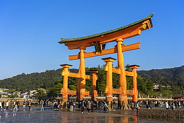 Tourists walking under the torii gate of Miyajima at low tide, Itsukushima, UNESCO World Heritage Site, Hiroshima Prefecture, Honshu, Japan, Asia