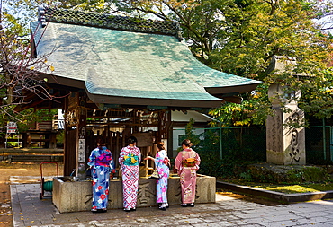 Japanese women in kimonos washing hands before entering the Tenmangu Shrine, Kyoto, Japan, Asia