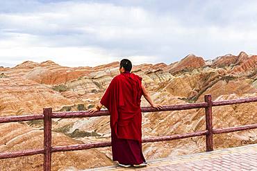 Monk and Eroded hills of sedimentary conglomerate and sandstone, Unesco World Heritage, Zhangye, China