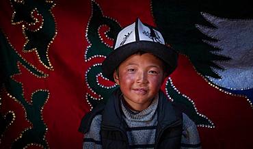 Young Kyrgyz with a kalpak, traditional hat. Image taken in a yurt in the mountains of Kyrgyzstan