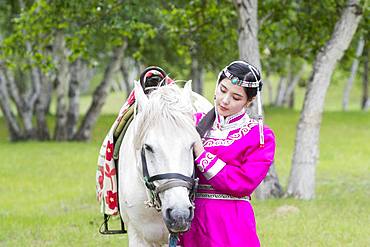 Mongol woman traditionnaly dressed with a horse, Mode, Bashang Grassland, Zhangjiakou, Hebei Province, Inner Mongolia, China