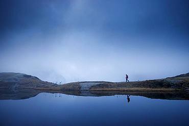 Hiker at Lake Lauzon (2008m), La Chapelle-en-Valgaudemar, Ecrins National Park, Hautes-Alpes, France