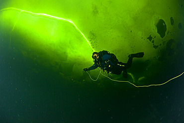 Scuba diver under ice and ice formation, Arctic circle Dive Center, White Sea, Karelia, northern Russia