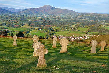 Granite discoid steles overlooking the village of Ainhoa (most beautiful village in France). In the distance, the Rhune mountain located on the border ridge between France and Spain, Basque Country, France