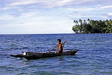 Boy and outrigger canoe Fergusson island Papua New Guinea