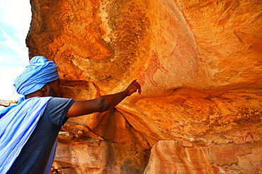 Moorish man looking at some cave paintings at the rock shelter of Agrour Amogjar discovered by french explorateur Theodore Monot. Atar. Adrar. Mauritania.