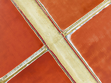 Saline ponds at the Bonanza salt works near Sanlúcar de Barrameda. The red colour depends on the level of salinity and is directly caused by the algae Dunaliella salina and brine shrimp. Aerial view. Drone shot. Cádiz province, Andalusia, Spain.