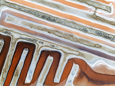 Saline ponds at the salt works near Chiclana de la Frontera. The orange-red colour depends on the level of salinity and is directly caused by the algae Dunaliella salina and brine shrimp. Aerial view. Drone shot. Cádiz province, Andalusia, Spain.