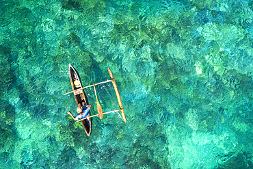 A fisherman with his traditional pirogue on Mayotte's turquoise-blue lagoon.