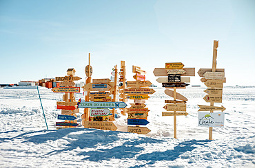 Village/town signs fixed on poles in front of the station/ Making and putting up a sign indicating the direction of one's home is a deeply rooted tradition in the stations. Concordia Antarctic Research Station, Dome C plateau, East Antarctica.