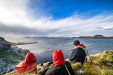 A contemplative break for the team of scientists. The ornithologist on the right has a camera to inspect the inside of the burrows to read the rings of banded birds. Mayes Island, Gulf of Morbihan. Kerguelen Archipelago.