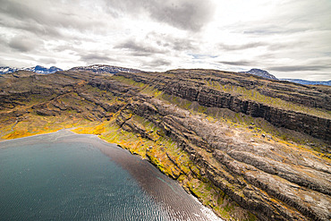 Landscape of southwestern Kerguelen, in Table Bay. Basaltic rock, sparse vegetation, characteristic low lenticular clouds.
