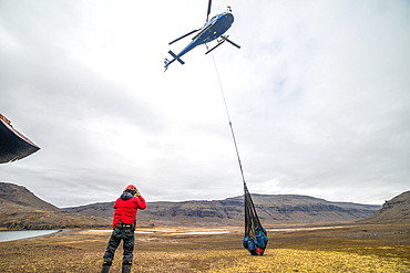Supplying the Val Studer hut by helicopter. The helicopter drops a net, or "sling", containing several drums filled with equipment and food. Kerguelen Archipelago