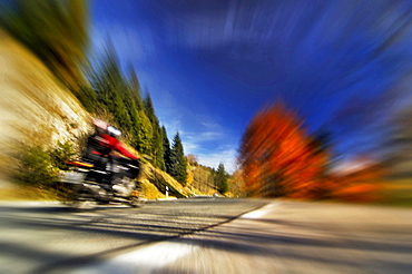 car driving on German alpine road at Bayrischzell colored trees on roadside landscape with mountains autumn mood