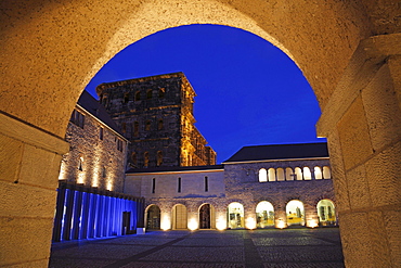 Porta nigra with archway and fountain court illuminated at night