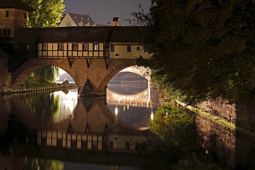 old historical bridge with houses crossing river Pegnitz illuminated at night Nuremberg francs Germany