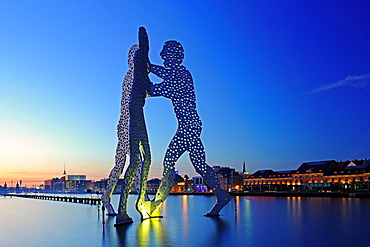 sculpture Molecule men 30 meter tall work made of aluminium by artist sculptor Jonathan Borofsky illuminated standing in river Spree at sunset mood Berlin Germany