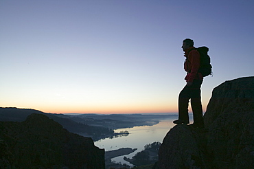 A walker above Lake Windermere on Todd Crag at dawn, Lake District National Park, Cumbria, England, United Kingdom, Europe