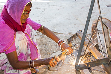 Women welding joints during the construction of solar cookers at the Barefoot College in Tilonia, Rajasthan, India. The Barefoot College is a worldwide charity, founded by Bunker Roy, its aims are, education, drinking water, electrification through solar power, skill development, health, women empowerment and the upliftment of rural people. Solar cookers save women having to walk to the froest to cut down wood for cooking, thus saving the forests, and a daily chore for woman.