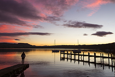 A woman by Lake Windermere at sunset, Ambleside, Lake District, UK.