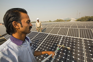 Workers washing the dust off solar panels at a 1 MW solar power station run by Tata power on the roof of an electricity company in Delhi, India, to make them more efficient.