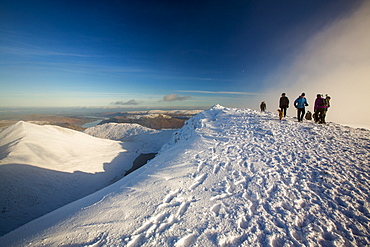 Walkers on Helvellyn summit in winter conditions, Lake District, UK.