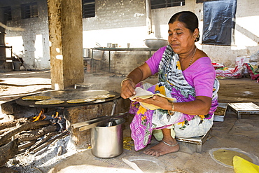 The Muni Seva Ashram in Goraj, near Vadodara, India, is a tranquil haven of humanitarian care. The Ashram is hugely sustainable, next year it will be completely carbon neutral. Its first solar panels were installed in 1984, long before climate change was on anyones agenda. Their energy is provided from solar panels, and wood grown on the estate. Waste food and animal manure is turned inot biogas to run the estates cars and also used for cooking. Solar cookers are also used, and the air conditioning for the hospital is solar run. 70 % of the food used is grown on the estate. They provide an orphanage, schools for all ages, vocational training, care for the elderly, a specialist cancer hospital withstate of the art machinary, and even have a solar crematorium. This shot shows a cook preparing chapatis on a biofuel stove.