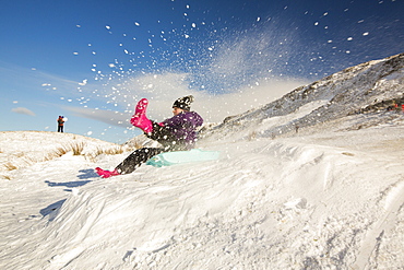 A girl sledging on Kirsktone Pass in the Lake District, UK