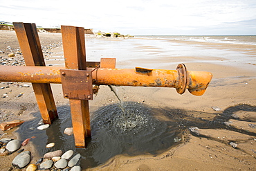 Raw sewage emptying directly onto the beach from a sewage pipe coming from a caravan park in Kilnsea, Spurn Point, Yorkshire, UK.