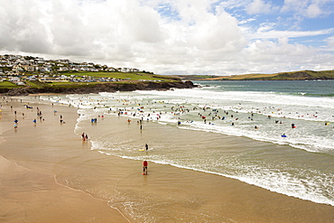 Surfers in the swell at Polzeath, Cornwall, UK.