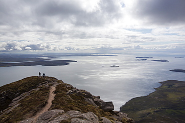 Walkers descending Ben Mor Coigach towards Loch Broom, looking towards the Summer Isles, Highlands, Scotland, UK.