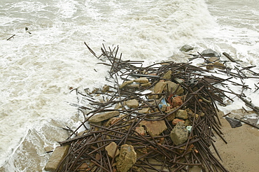 Waves crashing against debris on beach at Happisburgh on the fastest eroding section of the UK coast, Norfolk, England, United Kingdom, Europe