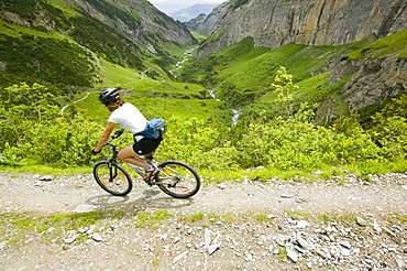 A women mountain biking in a high Alpine valley at Bargis in Switzerland, Europe