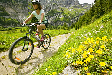 A women mountain biking in a high Alpine valley at Bargis in Switzerland, Europe