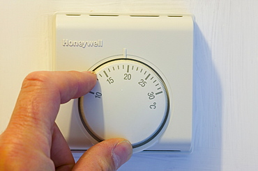 Setting the central heating thermostat at a cooler temperature to save energy