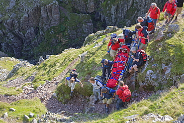 Members of Langdale Ambleside Mountain Rescue Team carrying an injured walker from the fells in Langdale, Cumbria, England, United Kingdom, Europe