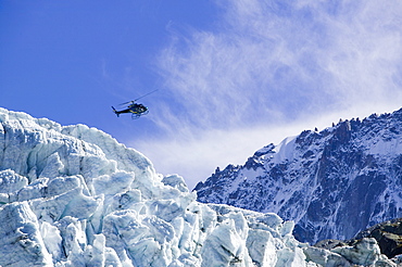 A tourist hericopter traverses melting seracs on the snout of the Argentiere Glacier, like most Alpine glaciers it is retreating rapidly due to global warming, Chamonix, Haute Savoie, France, Europe