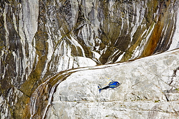 A tourist hericopter traverses melting seracs on the snout of the Argentiere Glacier, like most Alpine glaciers it is retreating rapidly due to global warming, Chamonix, Haute Savoie, France, Europe