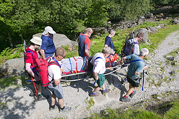 Members of Langdale Ambleside Mountain Rescue Team carrying a casualty off a peak in the Lake District, Cumbria, England, United Kingdom, Europe