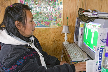 An Inuit woman playing on a computer on Shishmaref, a tiny island inhabited by around 600 Inuits, between Alaska and Siberia in the Chukchi Sea, United States of America, North America