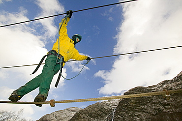 A climber crossing the steal rope bridge in Glen Nevis, Scotland, United Kingdom, Europe