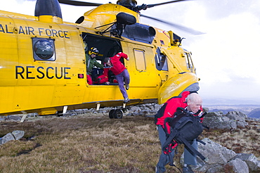 Mountain rescue team members and search dog handler with dog are dropped off by an RAF Sea King helicopter to start a mountain rescue search in the Lake District, Cumbria, England, United Kingdom, Europe